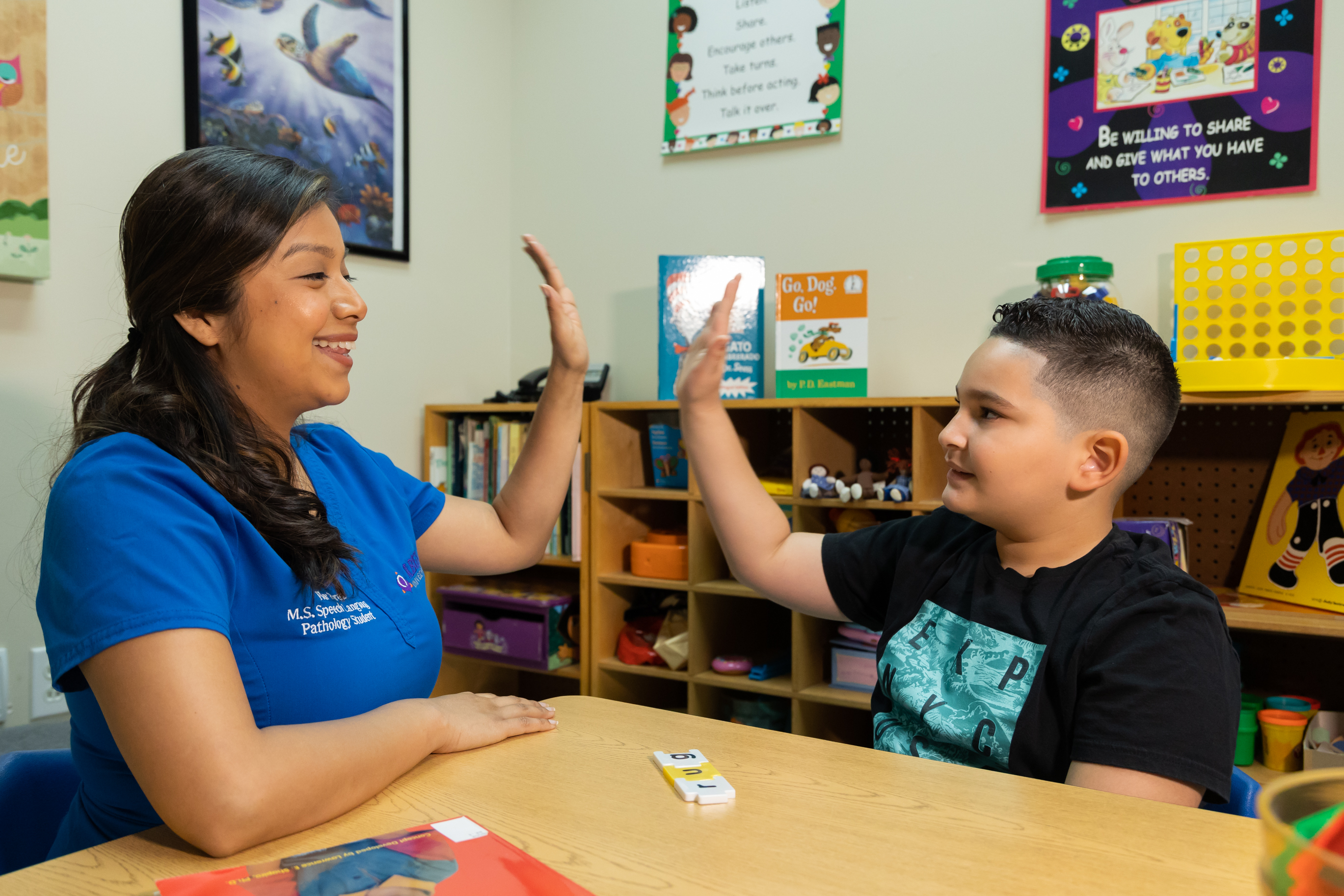 Therapist working with child in colorful classroom setting